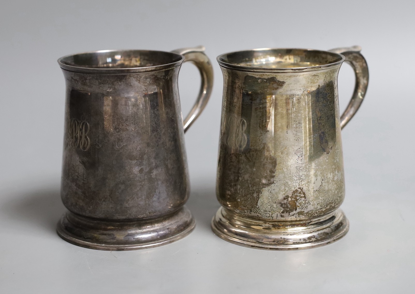A pair 1970's silver mugs with S-scroll handles, by Asprey & Co Ltd, London, 1973, height 10.8cm, 18.5oz, both with engraved monograms